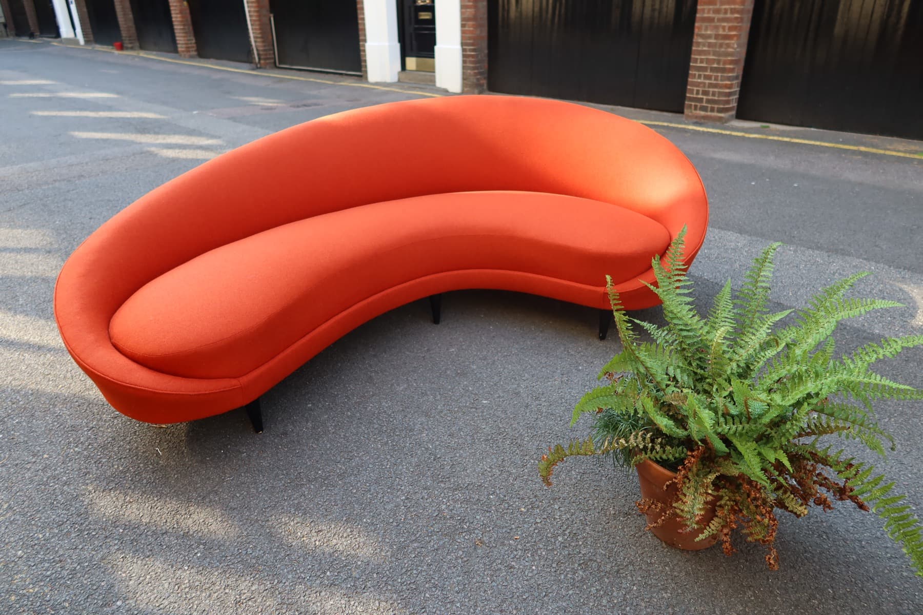 Curved orange sofa reupholstered with a smooth custom fabric finish