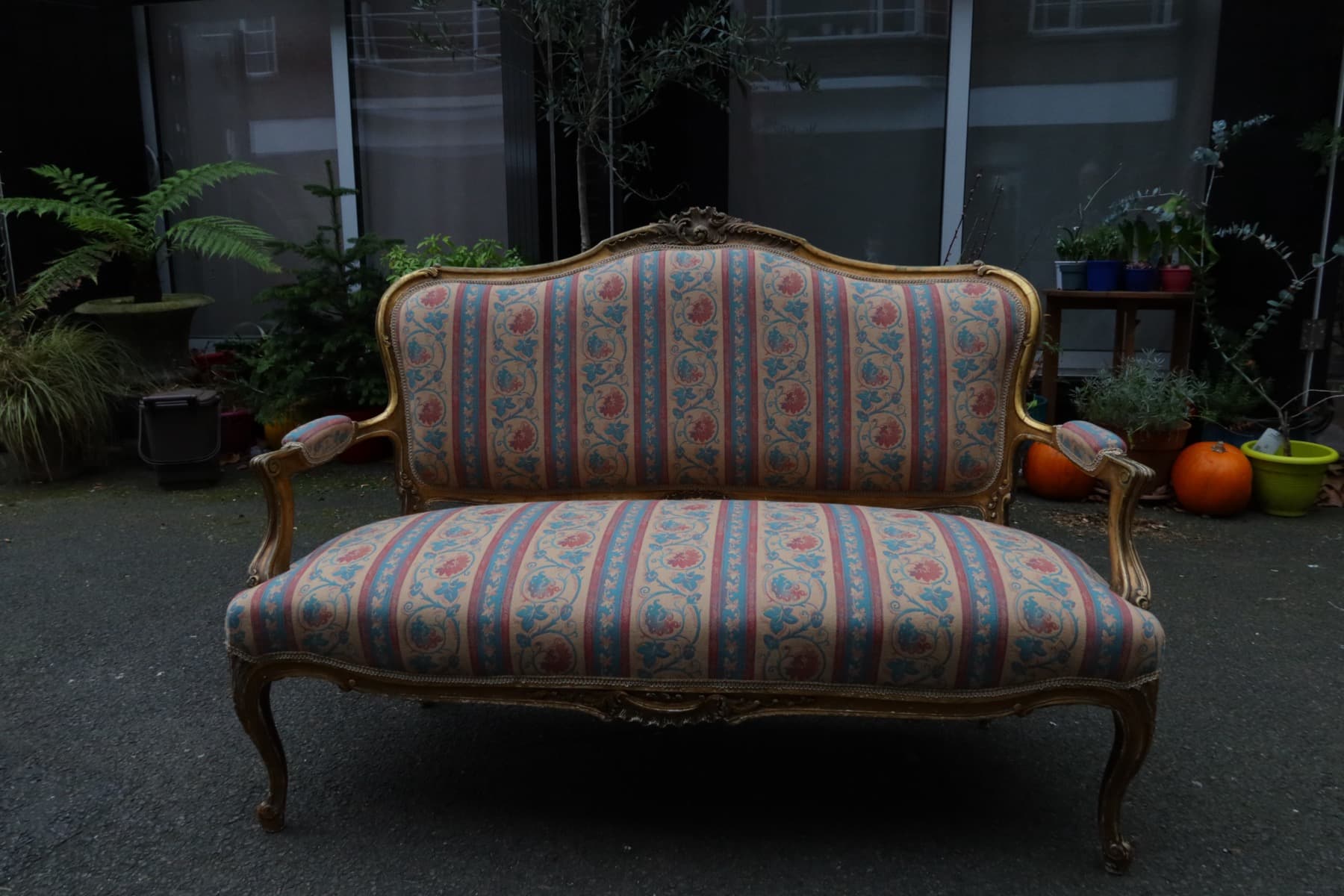 Vintage sofa with carved wooden frame that may be worth reupholstering
